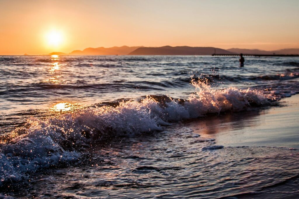close up view of the waves hitting the shore during sunset or sunrise