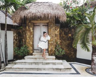 Asian woman with black curly hair enjoying in private villa in Canggu. Wearing white light tunic