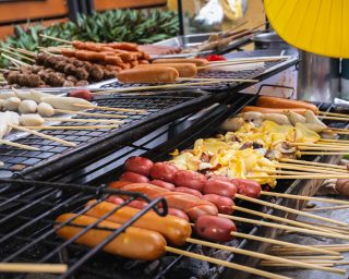 Simple street food in Bangkok, Thailand, meatballs, sausages, grilled squid on a stick